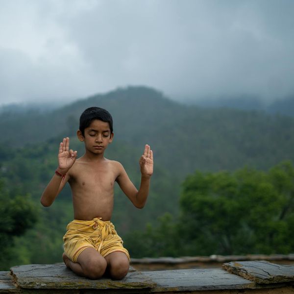 A person meditating peacefully outdoors with a serene natural background.